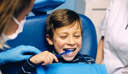 a child learning how to brush their teeth in the dentist’s office
