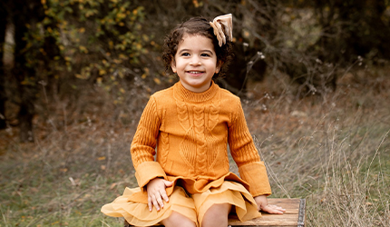 Child outdoors smiling at camera