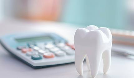 Model tooth on desk next to calculator