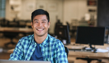 Man sitting at desk, smiling with dental bridge in DeSoto, TX