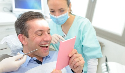 Man checking his smile after his dental bridge is in place