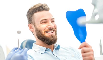 bearded man admiring his new smile after getting a dental crown