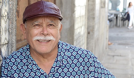 person leaning against a wall and smiling with dentures in DeSoto