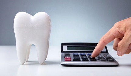 Man using calculator next to prosthetic tooth