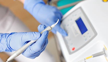 a gloved hand holding a dental laser