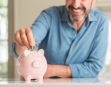 man putting coins into a pink piggy bank 