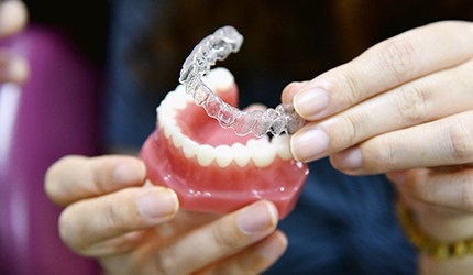 dentist showing a patient how to put Invisalign aligners on