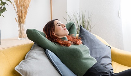 Woman relaxing on pillows on couch at home