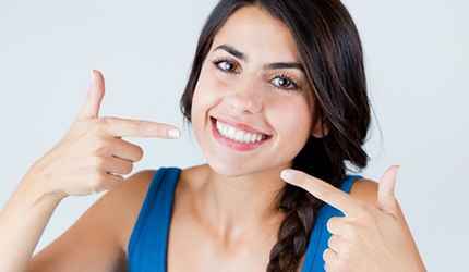 A patient pointing to her smile after receiving a smile makeover in DeSoto