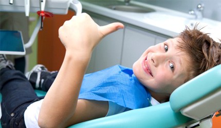 child giving thumbs up from dental chair 