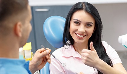 Woman in dental chair giving thumbs up