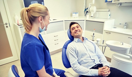 man in light blue dress shirt smiling at dentist