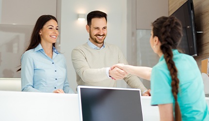 Receptionist shaking hands with two patients
