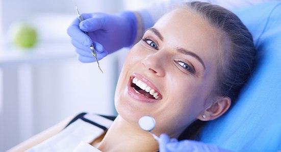 patient smiling while getting teeth cleaned