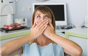 Woman in dental chair covering her mouth