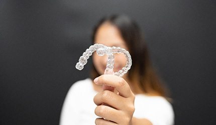 person holding two SureSmile aligners