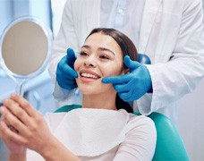 Woman with straight teeth smiling in mirror