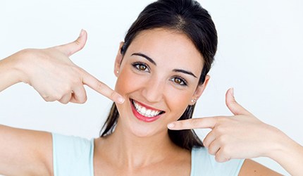 young woman pointing to her smile with white teeth 