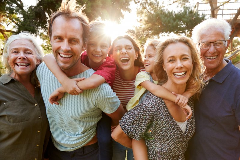 family smiling outside in the sun