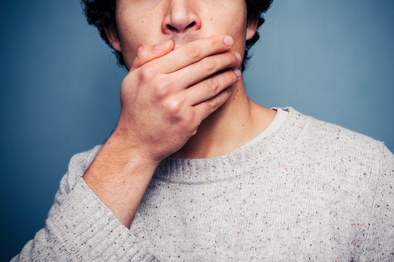 young man with hand over mouth