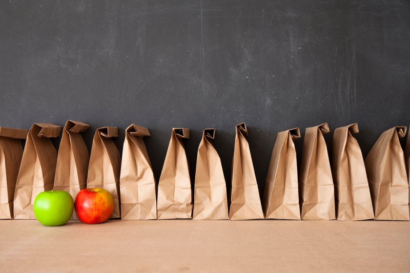 Row of brown lunch bags with two apples in front of it