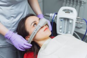 Dentist administering nitrous oxide to woman with dark brown hair