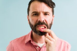 Man pulling down bottom lip to reveal red gums.